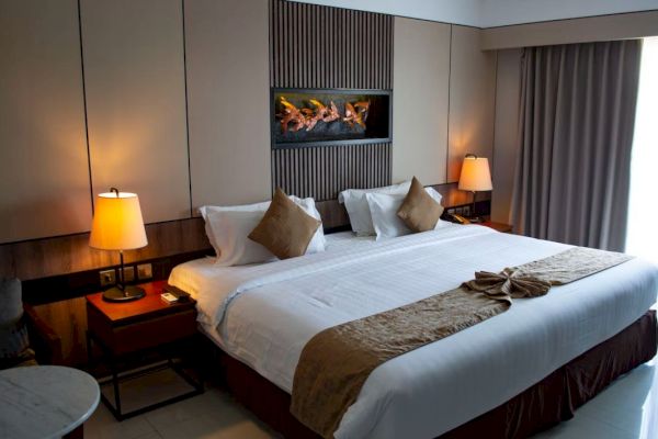 This image shows a neatly made hotel room bed with two nightstands, lamps, decorative pillows, and a wall art piece above the headboard.